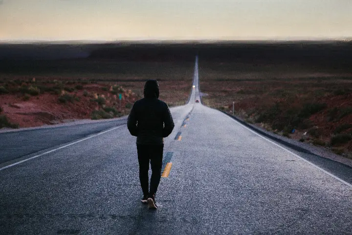 Pessoa andando sozinha por uma estrada. 
